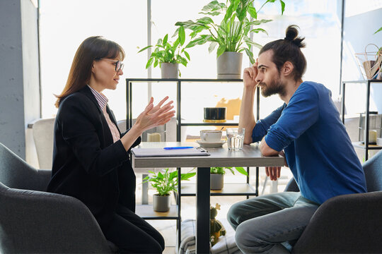 Middle aged female mental health specialist, insurance agent working with young male