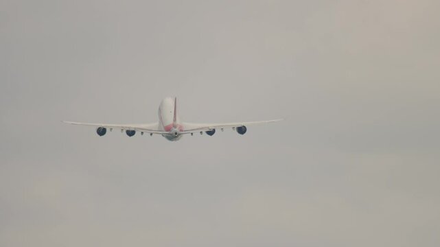 Footage of a wide-body, four-engine aircraft taking off, long shot, rear view