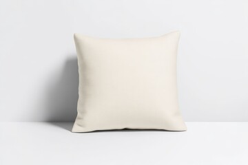 A simple, cream-colored cushion rests against a plain backdrop, showcasing its soft texture and minimalist design.