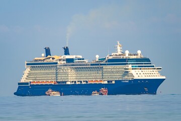 Cruise ship navigating calm waters under a clear sky near a coastal destination