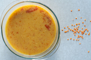 Homemade feshly prepared red lentil soup cooked with tomatos in a glass bowl. Top view.