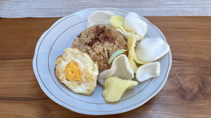 Top view of Nasi goreng- Indonesian fried rice with fried egg, chicken meat, chili, sausage, and crackers. Fried rice is a typical Indonesian street food