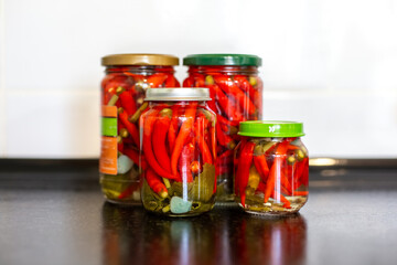 Jars of pickled red hot chili peppers in the kitchen. Preserves for the winter