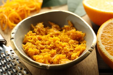 Orange zest, grater and fresh fruit pieces on table, closeup