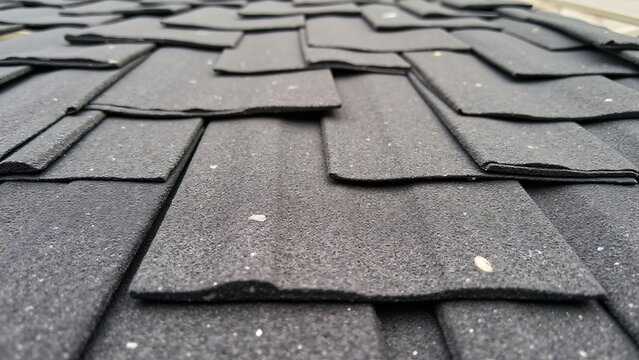 Asphalt shingles showing cracks, curling edges, and granule loss from weather exposure over time.
