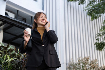 Confident Businesswoman Walking and Talking on Phone in Urban Cityscape with Coffee