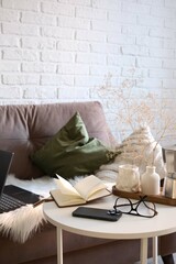 A Stylish and Functional Workspace Featuring a Laptop, mobile phone, notebook with glasses, books in bag on sofa and coffee break..