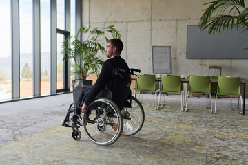 Obraz premium A director in a wheelchair sitting alone in an empty office, deeply reflecting on business strategies and decisions, contemplating the path forward with focused determination.