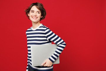 Side view young happy IT woman wear blue striped sweatshirt casual clothes hold use work on laptop...