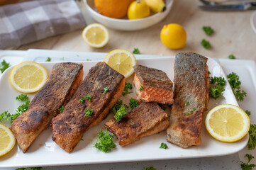 Pan fried salmon fillet with skin on a plate with garnish and lemon fresh and homemade cooked