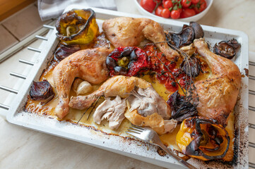 Roasted chicken legs with oven vegetables on a baking tray fresh and homemade cooked