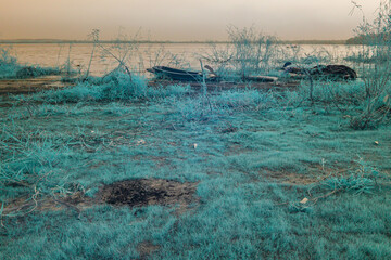 Infrared photography, a tranquil yet slightly melancholic landscape with wooden boat lying on the...
