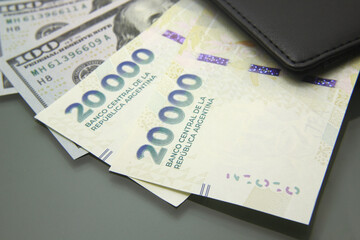 Argentine and dollar money, various bills inside a wallet, close-up on dark background. Twenty thousand cash bills