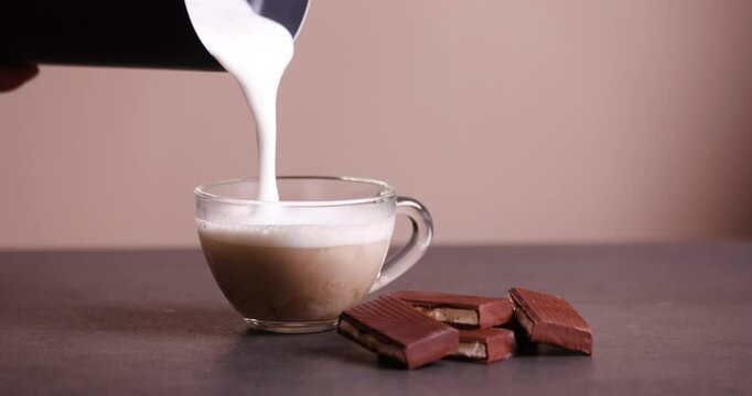 aromatic coffee with milk in a cup on a light background and chocolate lying nearby
