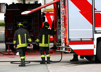 firefighters with protective helmets during an emergency intervention are taking the equipment from...
