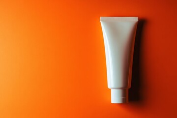 Minimalist white cosmetic tube on vibrant orange background