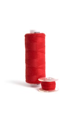 On a white background lies a red spool of thread and a bobbin.