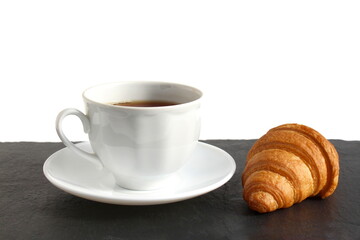 A cup of coffee with a croissant is on the table.