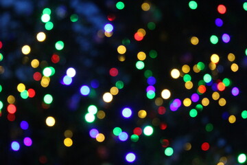Bright multi-colored lights shine on a black background. Blurred background.