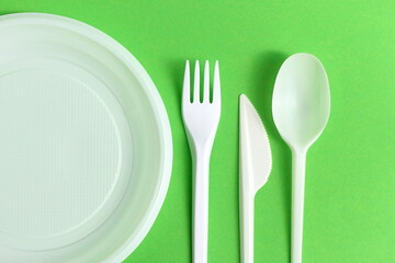 Disposable plastic white tableware lies on a green background.