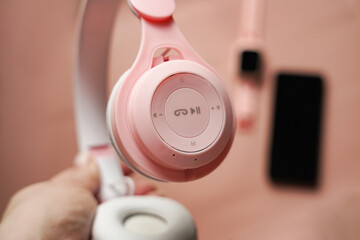 Close up of pink wireless headphones on blurred background with gadgets mobile phone and smartwatch...