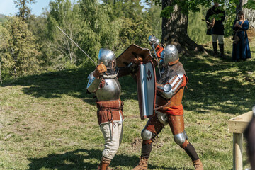 Medieval fighters in medieval armor with shield and sword demonstrate medieval fighting