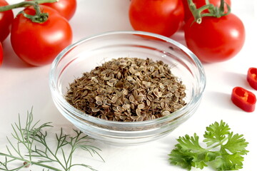 Seasoning dill seeds lie in a glass cup on a white background.