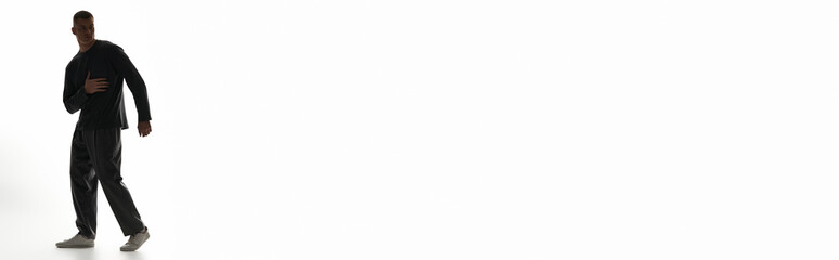 A young man showcases his dance moves in a bright, spacious studio filled with light.