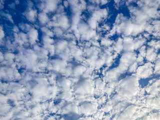 Obraz premium Image shows a candid scene of a sky with scattered, fluffy clouds against a clear blue backdrop Clouds are irregularly shaped and appear at varying distances, giving depth to the scene No discernib