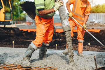 Construction workers pouring concrete at a building site during daylight in an urban area