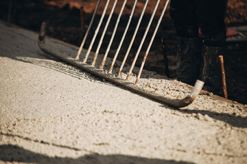 Workers leveling fresh concrete at a construction site during daylight hours in an outdoor setting