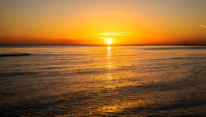 Obraz premium Stunning sunset over calm ocean waters. Golden hour light bathes the sea in warm hues, creating a tranquil and serene atmosphere. Perfect for travel, nature, and relaxation themes.