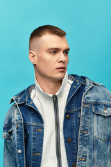 Obraz premium A stylish young man gazes thoughtfully to the side with a confident expression, dressed in denim.