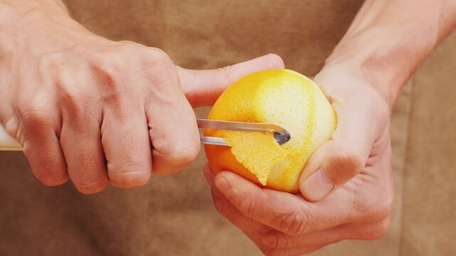 bartender makes a cocktail in a glass with orange peel, barman peeling orange or lemon. 