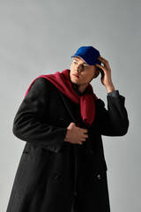 A handsome young man showcases a trendy outfit with a hat and scarf in a stylish indoor setting.