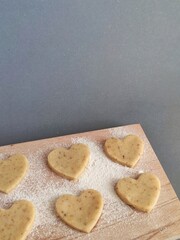 Freshly prepared heart-shaped cookies on a floured board
