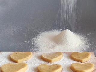 Freshly prepared heart-shaped cookies on a floured board