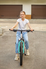 Obraz premium Young girl riding bicycle on quiet street during daylight in suburban area
