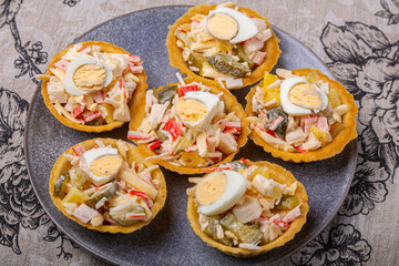 Salad with crabs and pineapples in tartlets on a plate decorated
