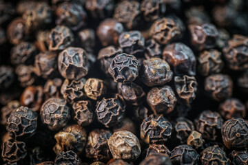 A close-up macro image of whole black peppercorns, showcasing their rich texture and dark brown tones. Perfect for culinary and spice-related themes.