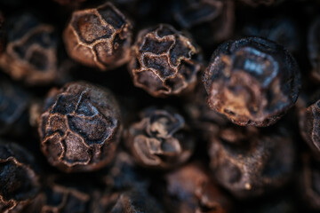 A close-up macro image of whole black peppercorns, showcasing their rich texture and dark brown tones. Perfect for culinary and spice-related themes.