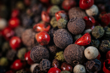 Close-up macro of colorful peppercorn mix featuring black, white, red, and green peppercorns. A vibrant blend of textures and spices, ideal for culinary and seasoning themes.
