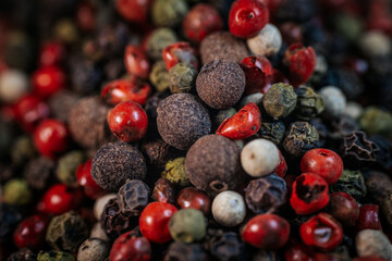 Close-up macro of colorful peppercorn mix featuring black, white, red, and green peppercorns. A vibrant blend of textures and spices, ideal for culinary and seasoning themes.