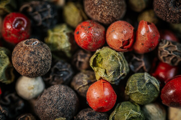 Close-up macro of colorful peppercorn mix featuring black, white, red, and green peppercorns. A vibrant blend of textures and spices, ideal for culinary and seasoning themes.