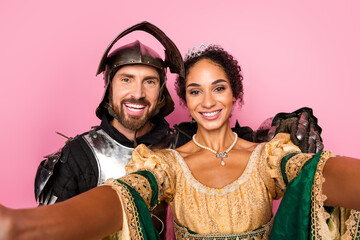 Couple Posing in Medieval Inspired Costumes with a Playful Vibe Against a Pink Background for a Fun...