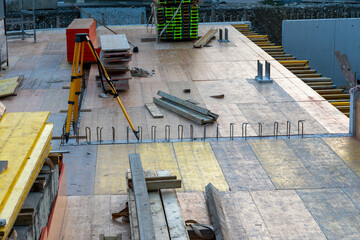 Wooden slabs on the basement ceiling build the foundation for further work on a construction site for an apartment house. Yellow tripod for theodolite is standing on the slabs.