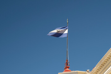 Isolated El Salvador flag waving against blue sky in San Salvador historical center. Independence,...