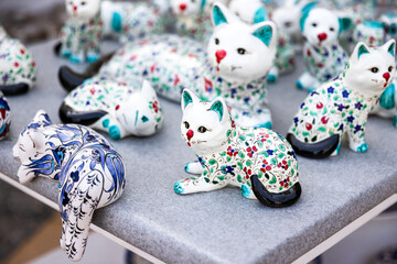 White ceramic cats with oriental patterns are on a counter