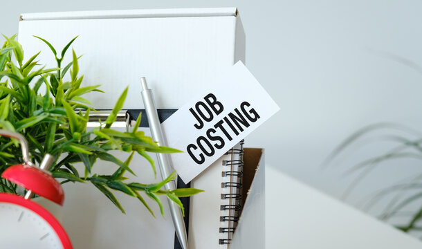 Job Costing text on Paper card on a cart with office items on the table