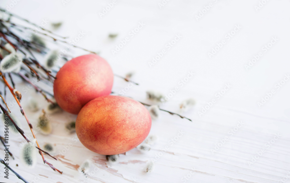 Wall mural Two red Easter eggs and spring fluffy willow branches on a wooden white surface, copy space, soft focus. Easter background with holiday symbol